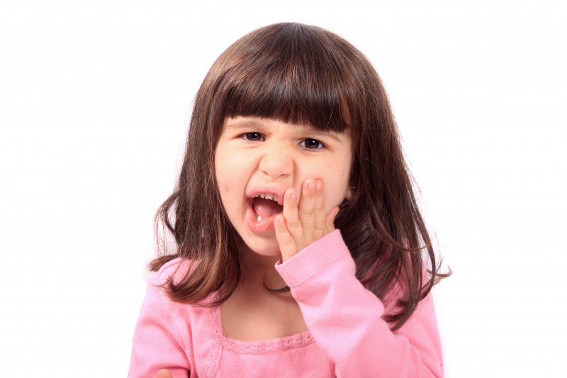 Child holding their cheek due to a toothache