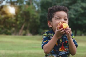 young child eating an apple outside